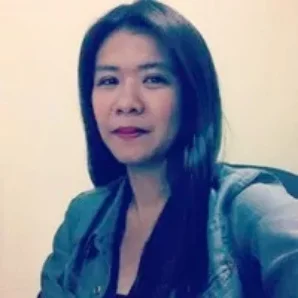A woman with long hair in a jacket, meeting indoors.