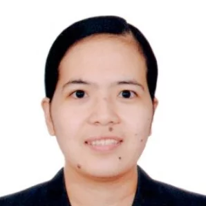 Meet the team member: a dark-haired person smiling in a black suit against a white background.