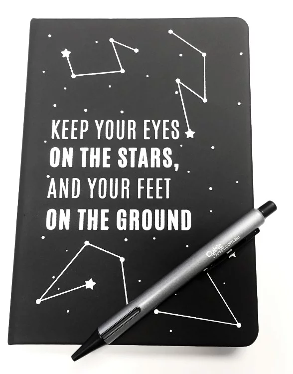 black notebook printed with quote and a pen