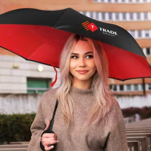 Woman with branded umbrella featuring Trade Group logo, in an urban setting.