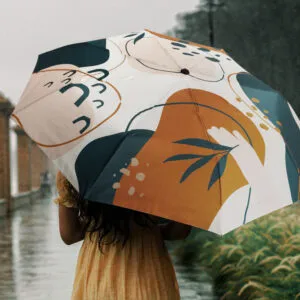 Outdoor elegance: person in yellow dress with colorful umbrella walking in rain.