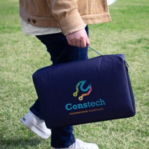 A person strolls across the grass, carrying a navy blue bag with the Constech logo, a perfect example of products for conference promotions.