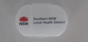White oval container featuring a red emblem design, branded with Southern NSW Local Health District, ideal for storing pharmaceutical essentials.