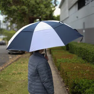 Person holding a large black and white umbrella, perfect for featured articles on sidewalk styles.