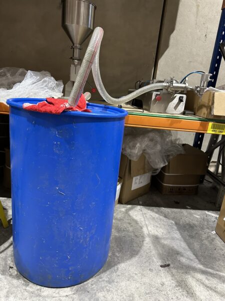 Large blue barrel with hoses and machinery for fill locally branded hand sanitiser production.