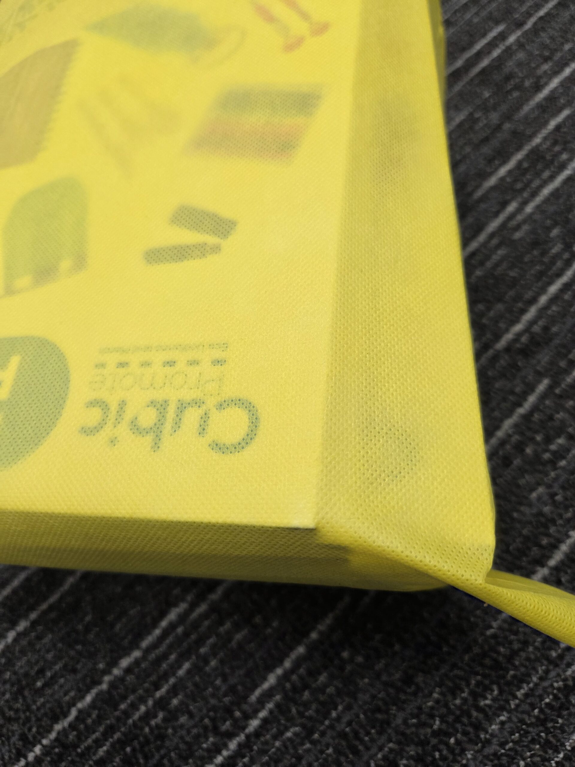Yellow fabric folder on a dark striped surface, similar to those in Conference Bags collections.