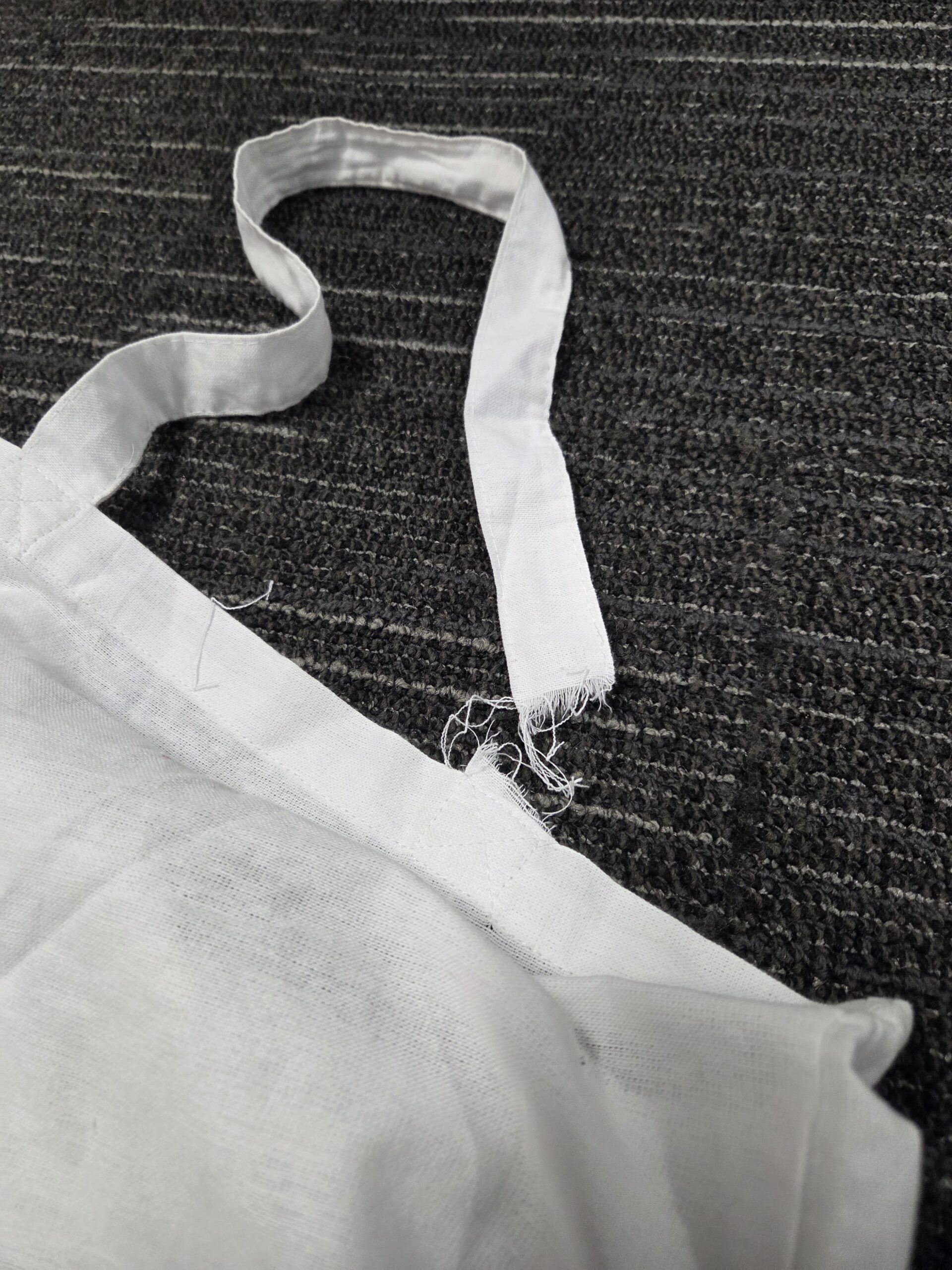A white cloth strap from custom branded tote bags lies on a dark textured surface.