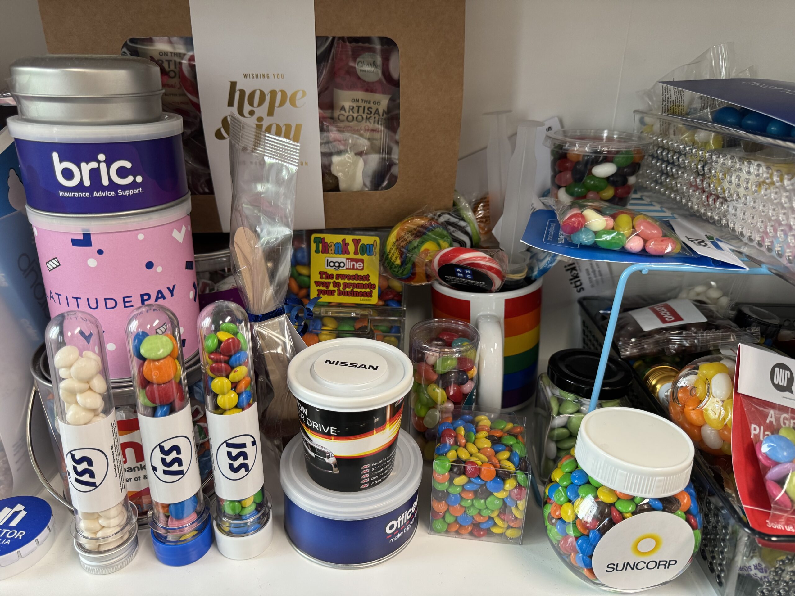 Assorted jars and containers with colorful candy and Cubic Promote branded merch on a shelf.