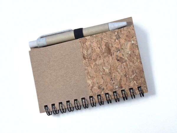 Brown spiral notebook with cork detail and pen—what are promotional eco friendly items like this?.