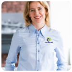 Smiling woman in blue shirt with a logo, standing indoors, focused on business goals.