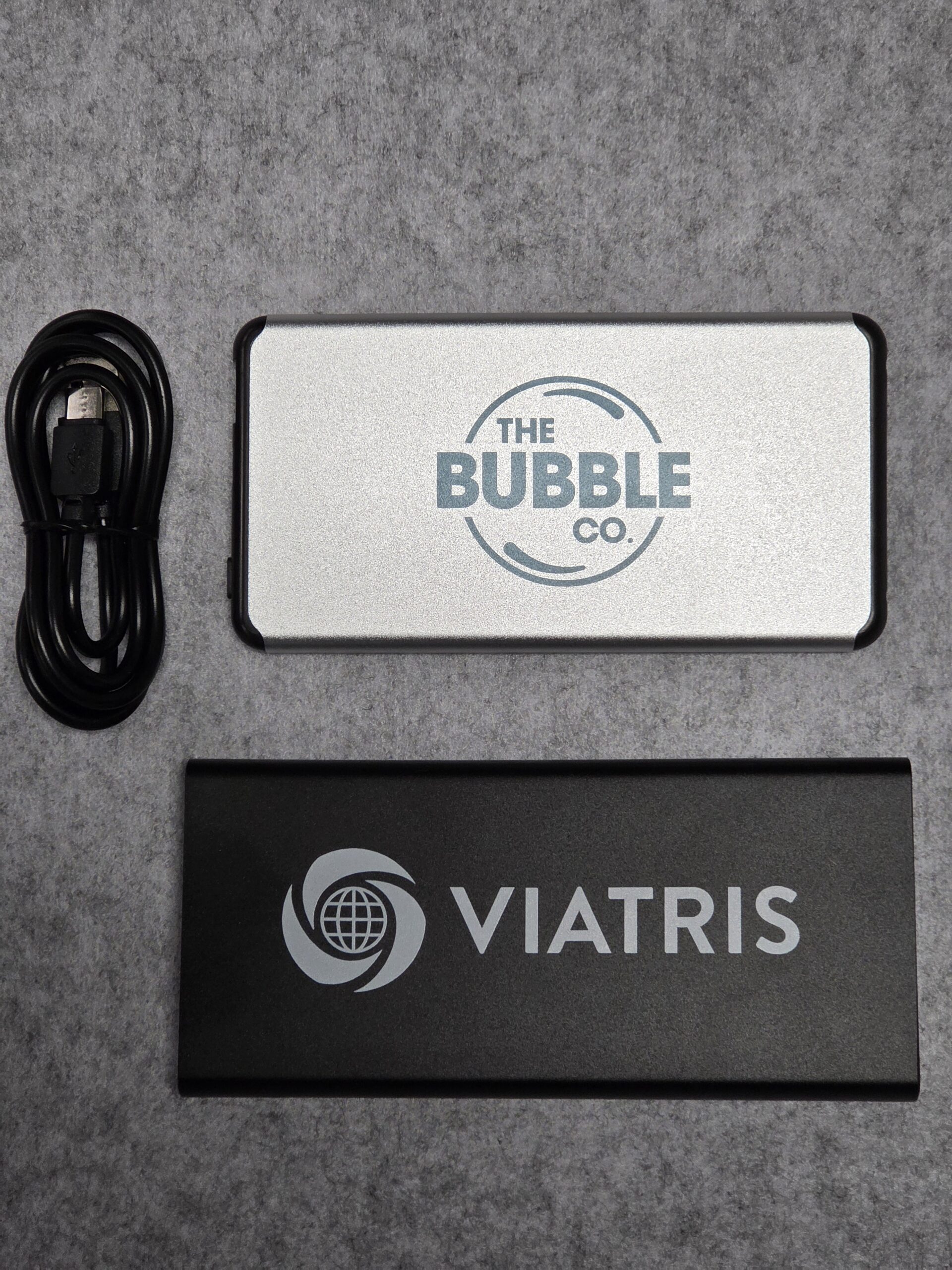 Two branded power banks and a USB cable on a grey surface, perfect for your power bank needs.