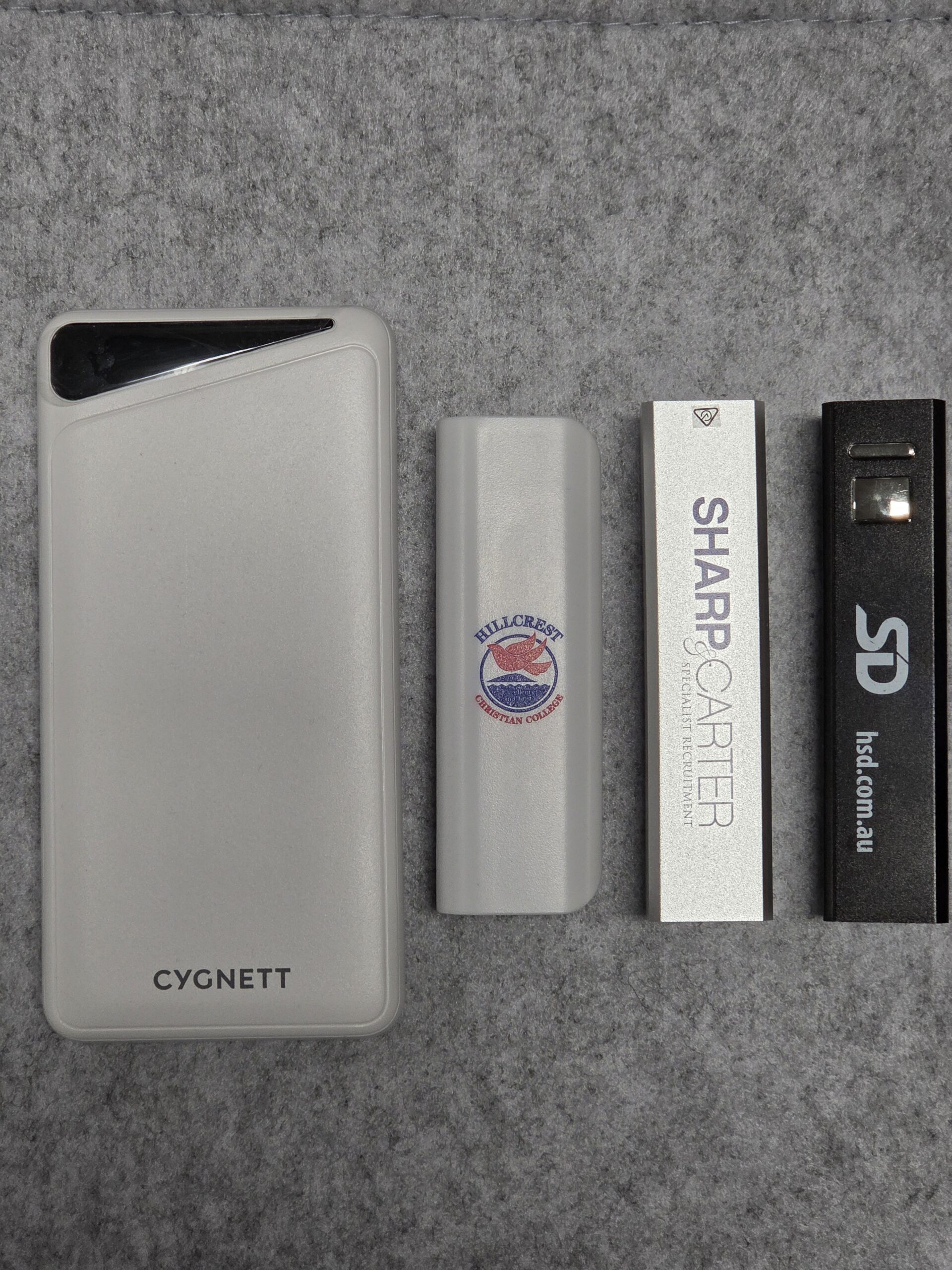 Four rectangular USB power banks on a gray surface, one labeled "CYGNETT," others with logos.