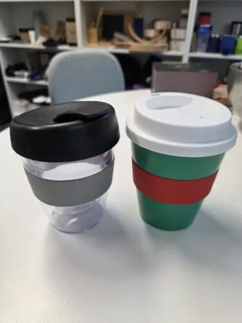 Two reusable cups with lids and bands, perfect as a promotional mugs guide in office settings.