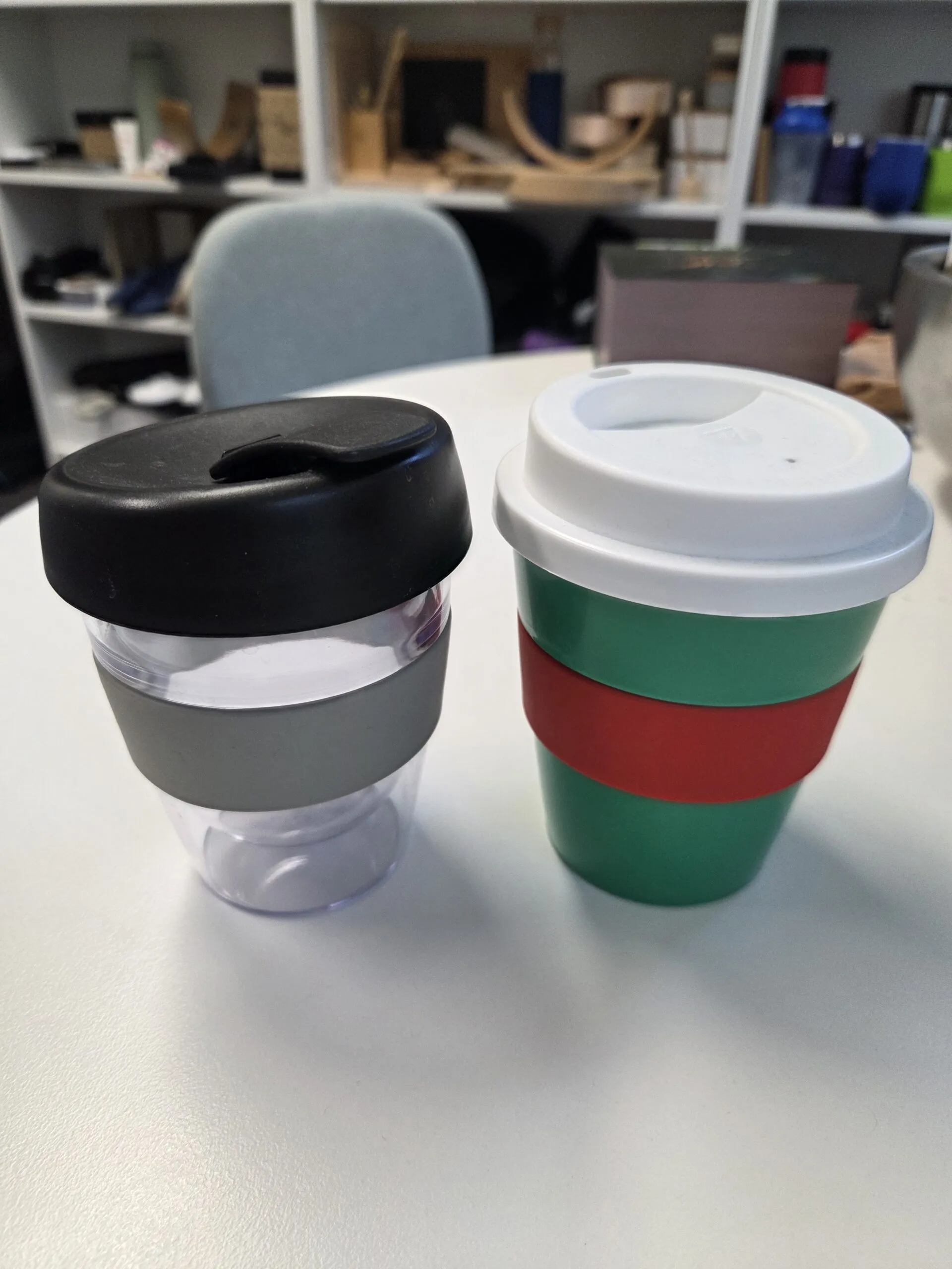 Two reusable cups with lids and bands, perfect as a promotional mugs guide in office settings.