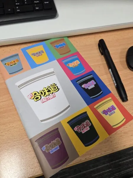 Notebook with colorful cup designs on a wooden desk, perfect for user generated content.