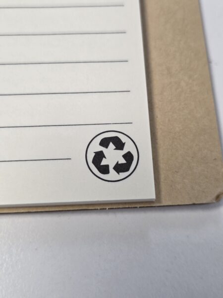 Notebook page with qsuper recycle symbol in the corner, next to a brown cover.