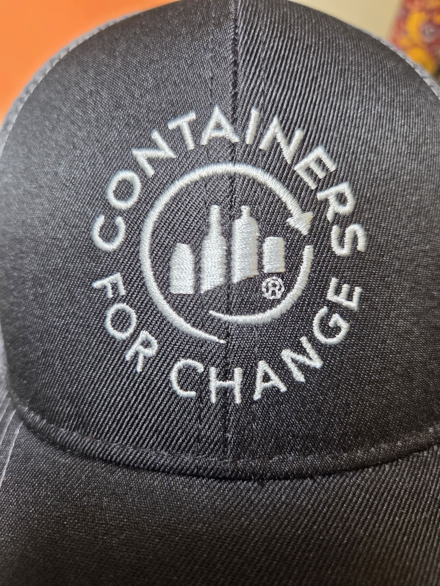 Black cap featuring the Containers for Change logo embroidered above three bottle icons.