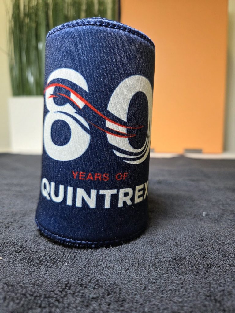 Navy drink holder with 60 years of QUINTREX logo, set on a dark surface.