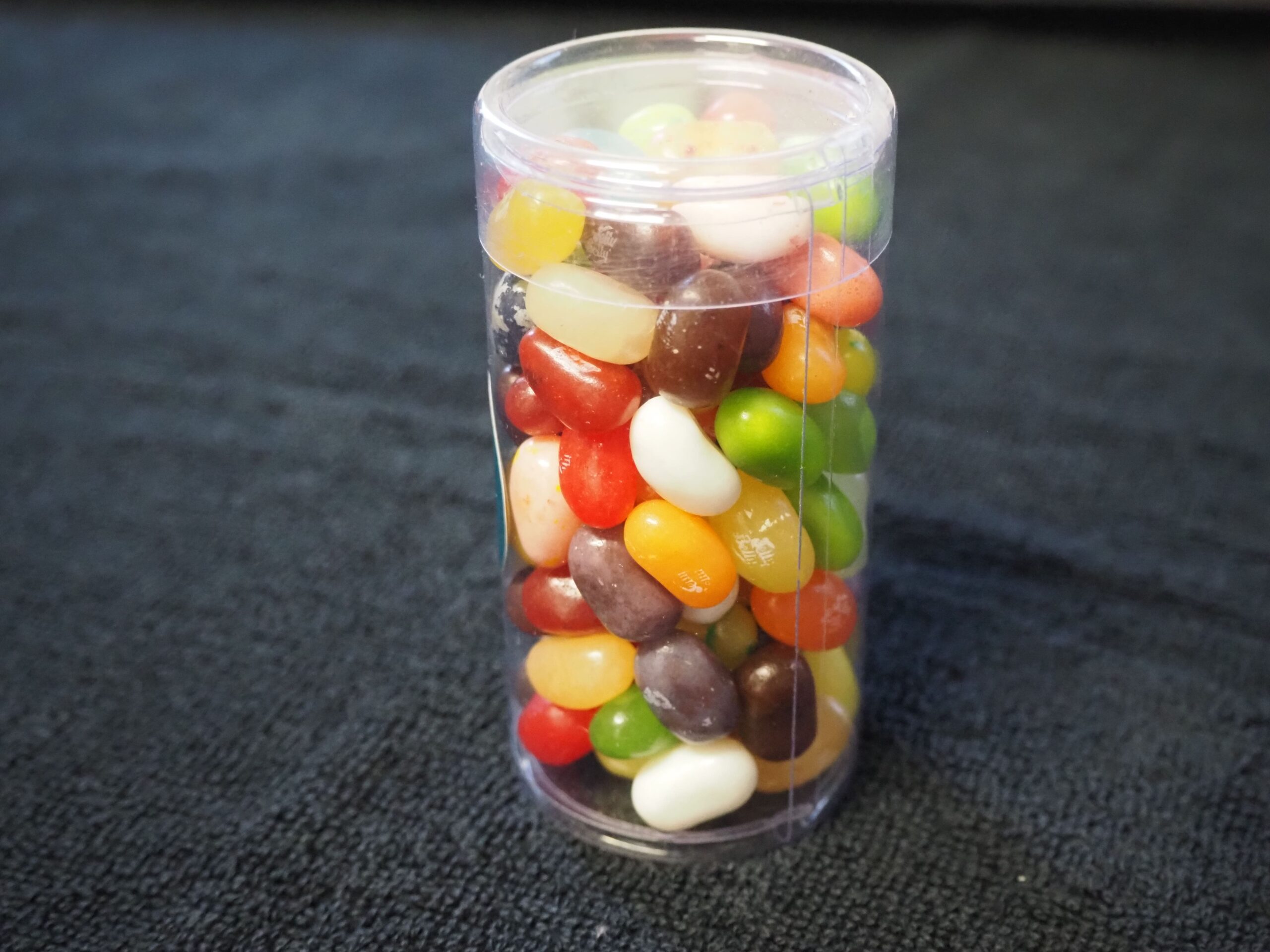 A clear plastic container of jelly beans sits on a dark surface, like a Suncorp Bank client story.
