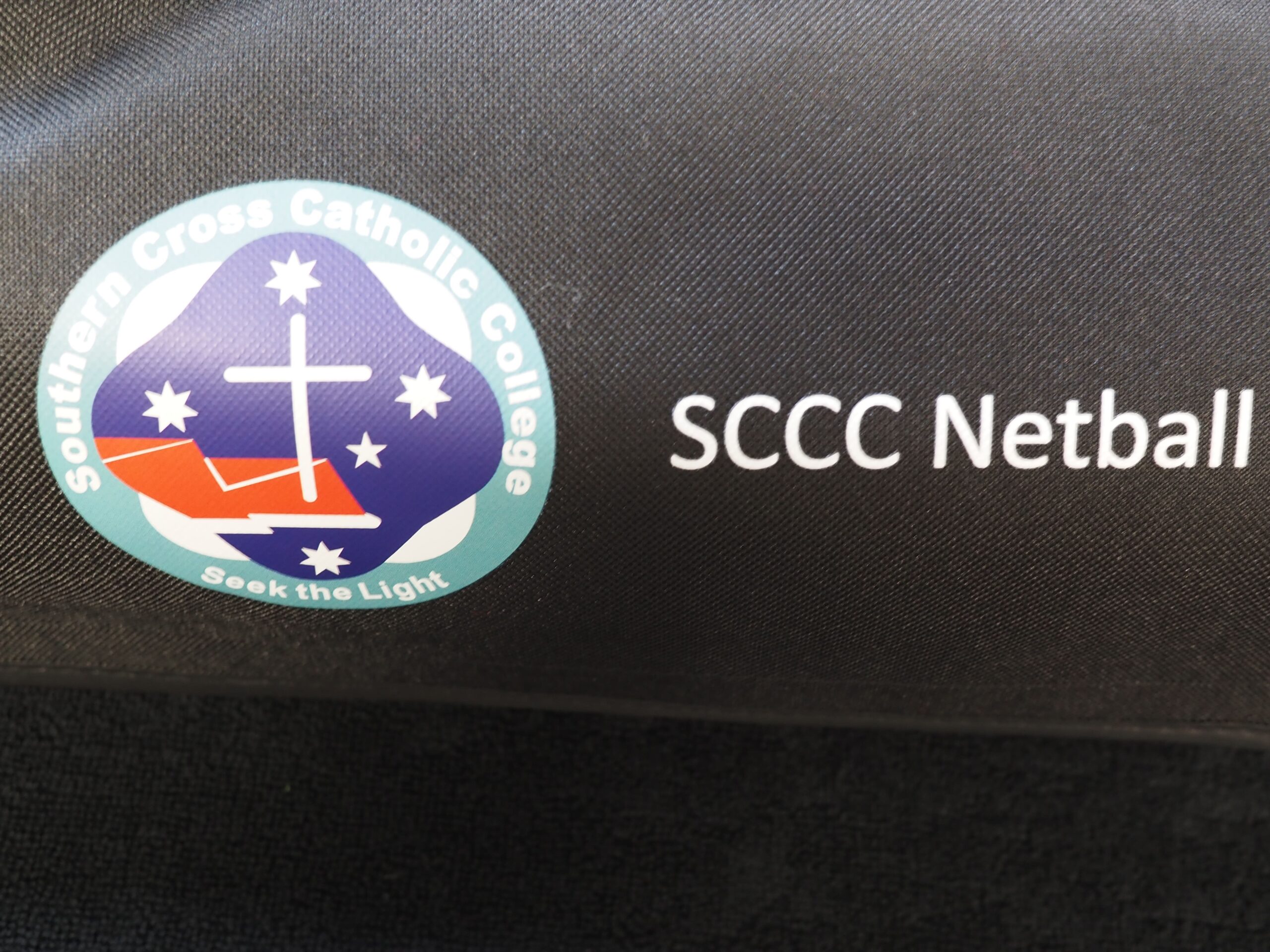 Southern Cross Catholic College Netball logo displayed on a sleek black background.