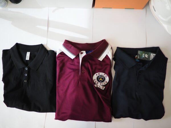 Three folded polo shirts—black, maroon with a patch, and navy—neatly arranged side by side.