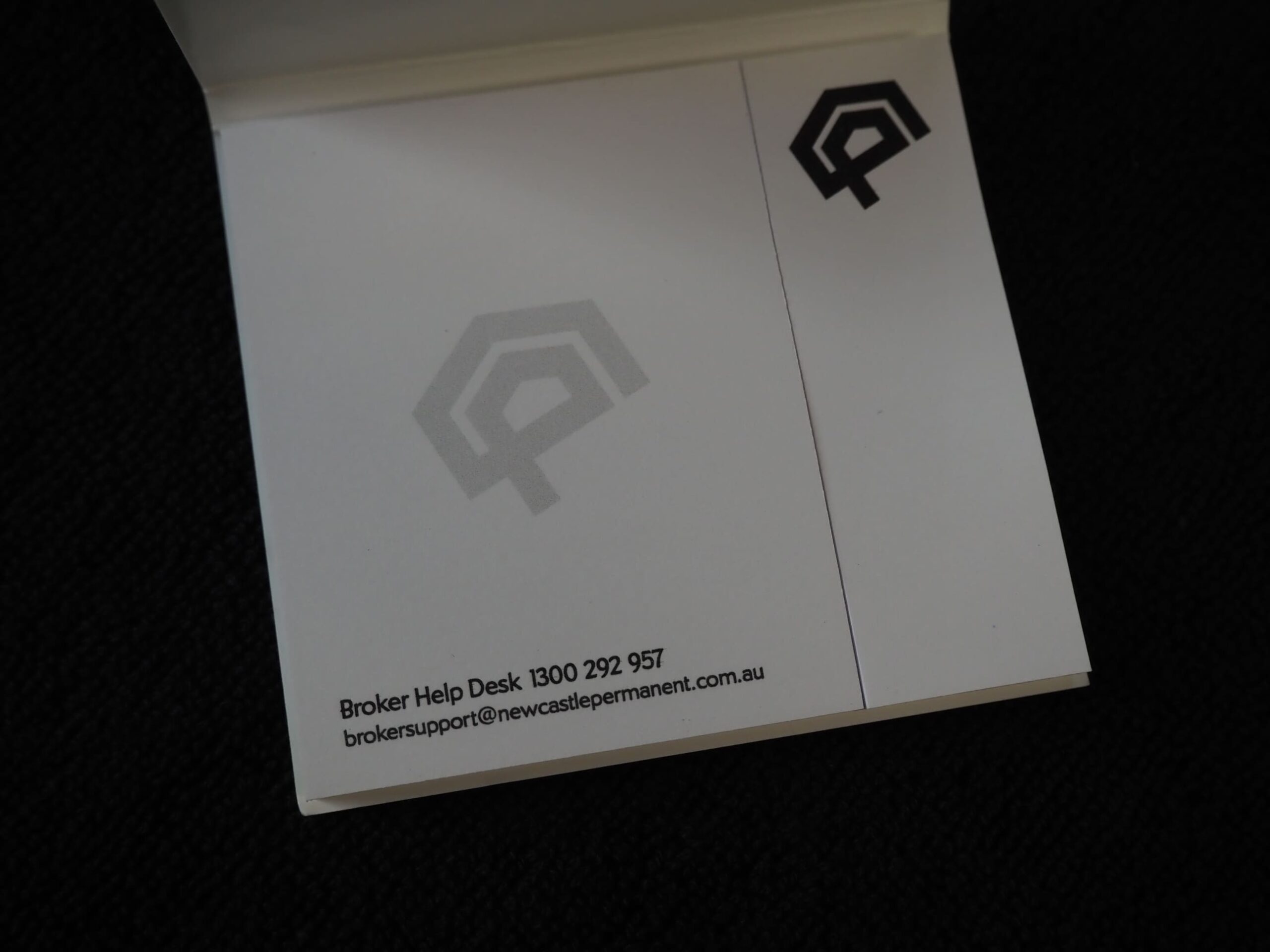 A notepad with a logo, home loans info, and broker help desk contact details at the bottom.