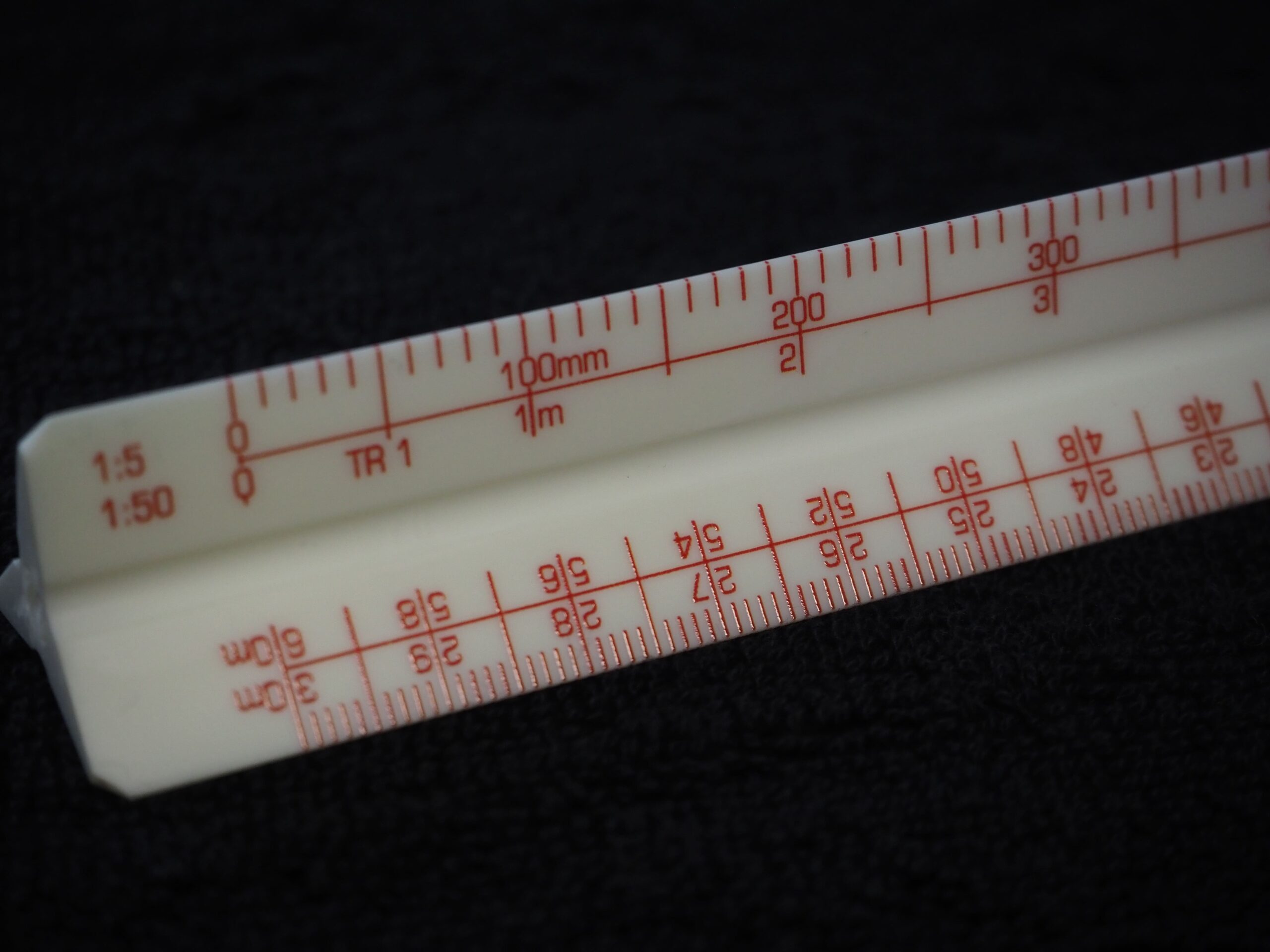 A close-up of a white triangular scale ruler with red markings, featured in a Bose client story.