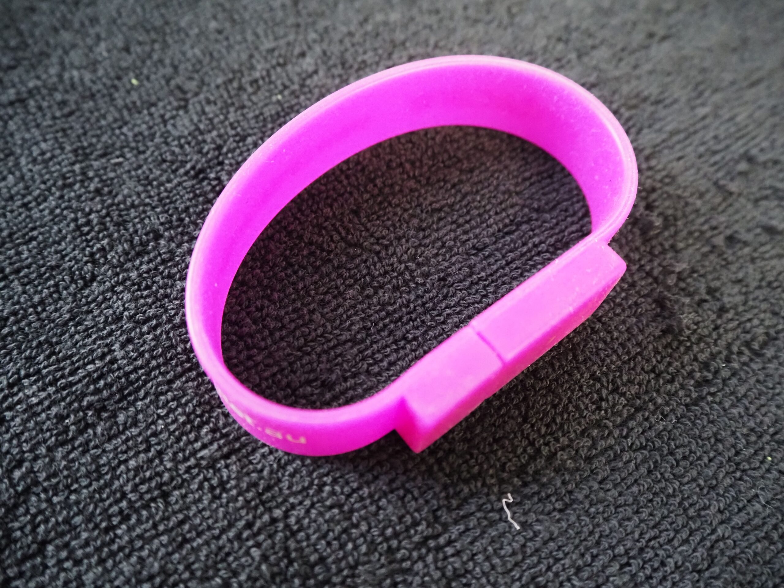 A pink silicone wristband on a textured black surface, sharing a Centacare client story.