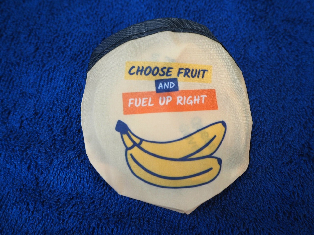 A pouch with bananas and Era Polymers text: Choose fruit and fuel up right on a blue towel.