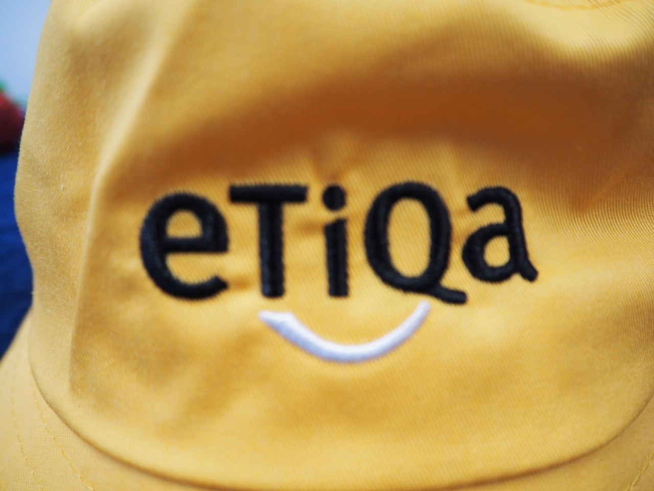Yellow fabric with Etiqa Australia and a white embroidered smile below the letters.