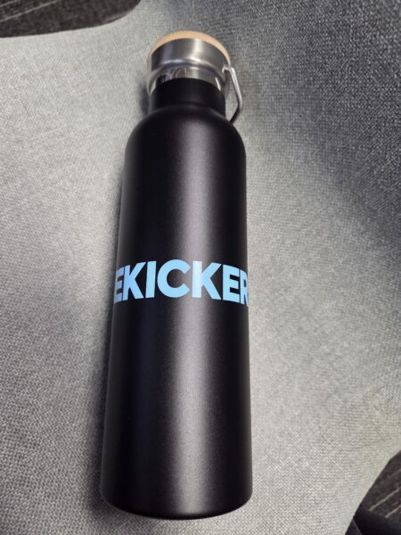 Black water bottle with blue rebrand KICKER text on a gray textured surface.