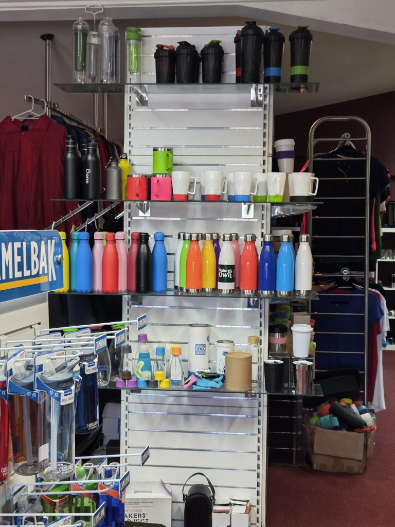 Shelves display colorful water bottles and mugs, showing why promotional products work.