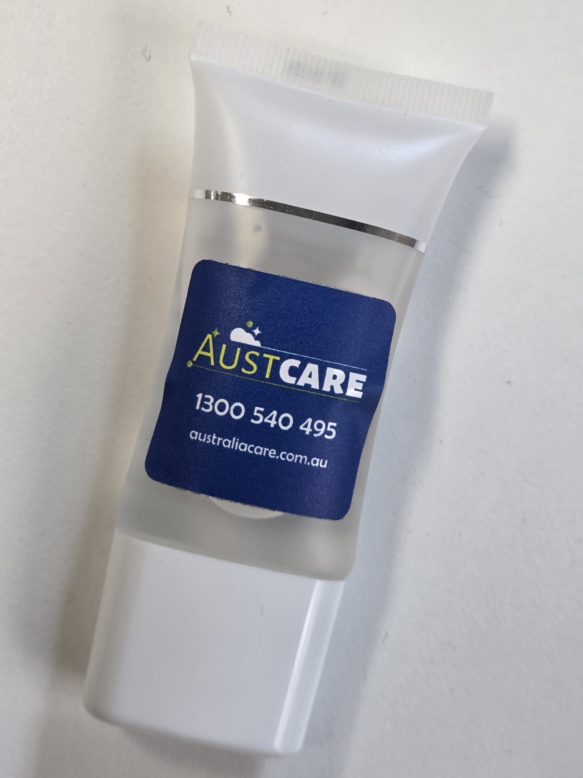 Small clear tube labeled Austcare with a blue sticker, phone, website—part of our Client Story.