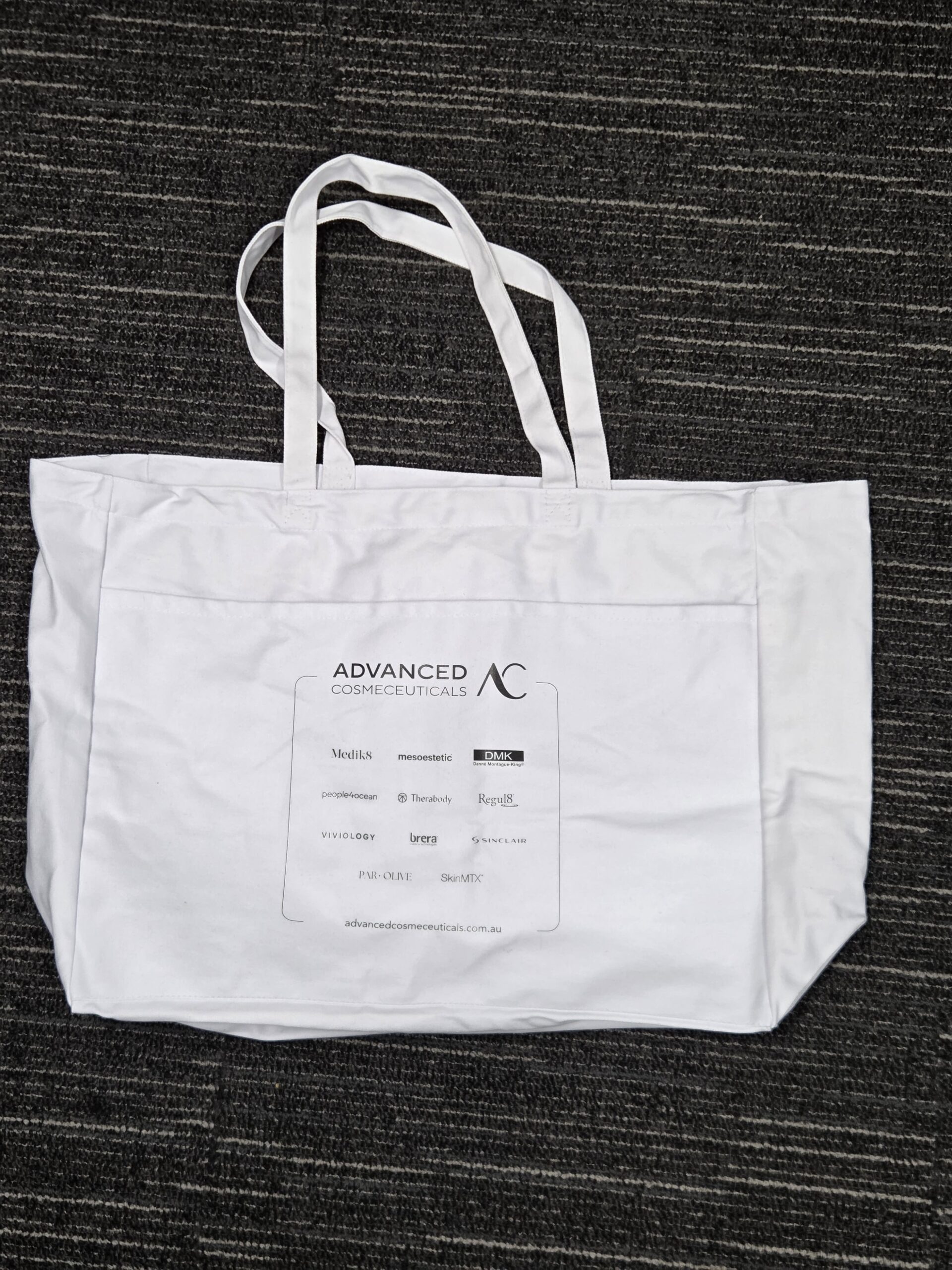 White tote bag with Advanced Cosmeceuticals logo—perfect for the satisfied customer.