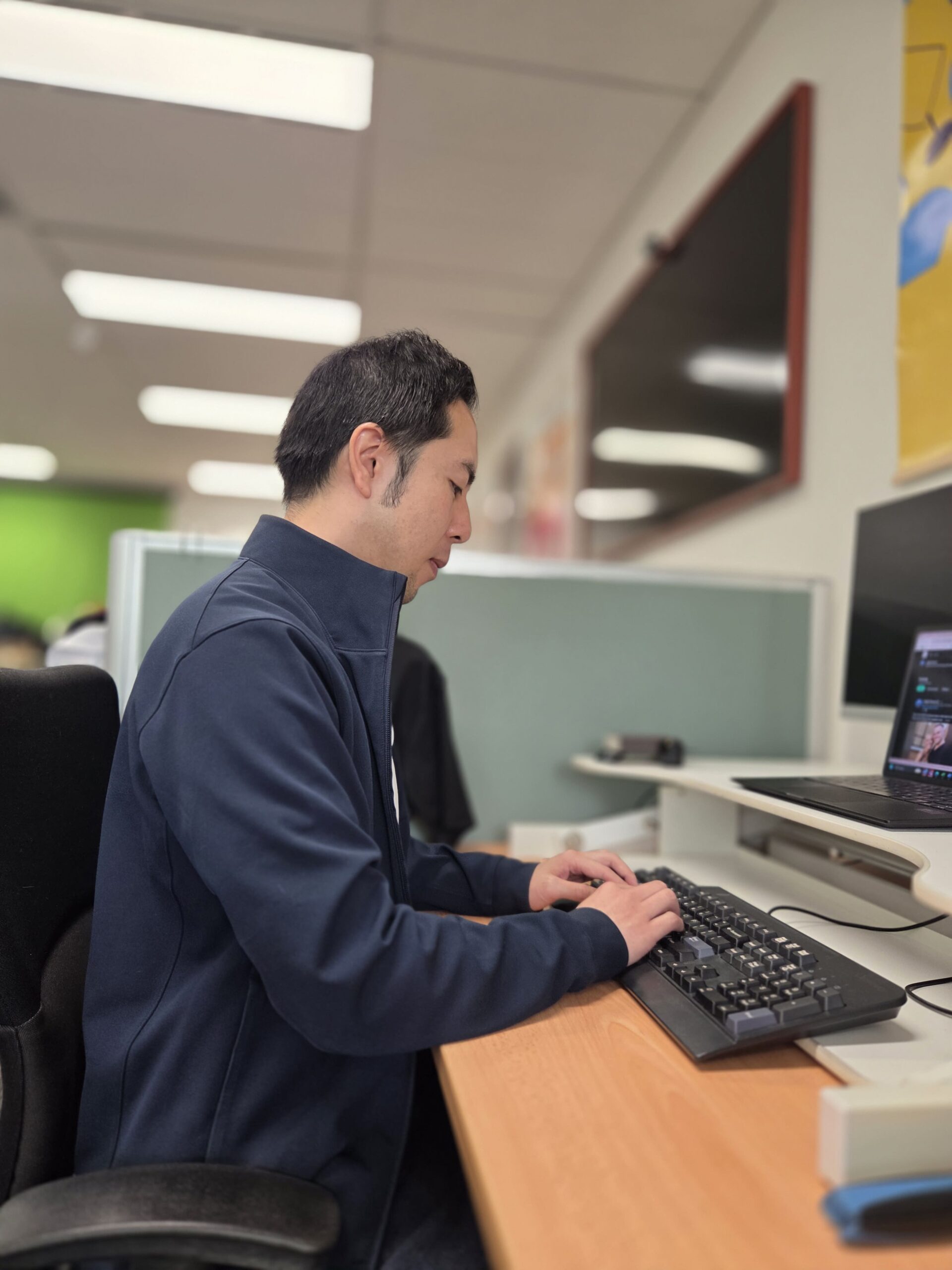 Man typing at an office desk; Cubic Promote is a trusted promotional products supplier.