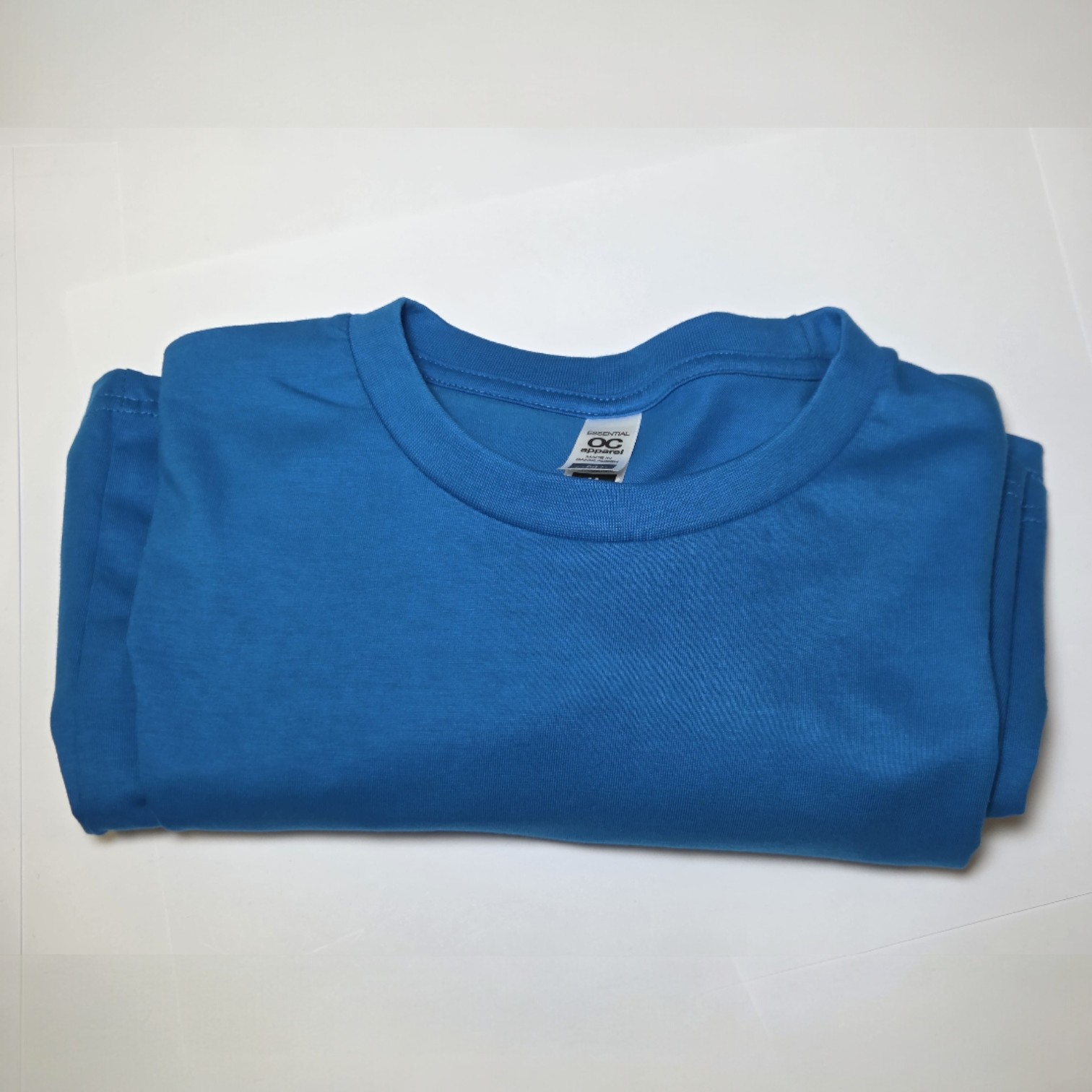 A folded blue t-shirt in classic branding colours on a white surface.
