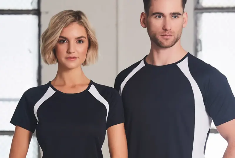 Two people wearing matching cool dry shirts in black and white standing indoors.