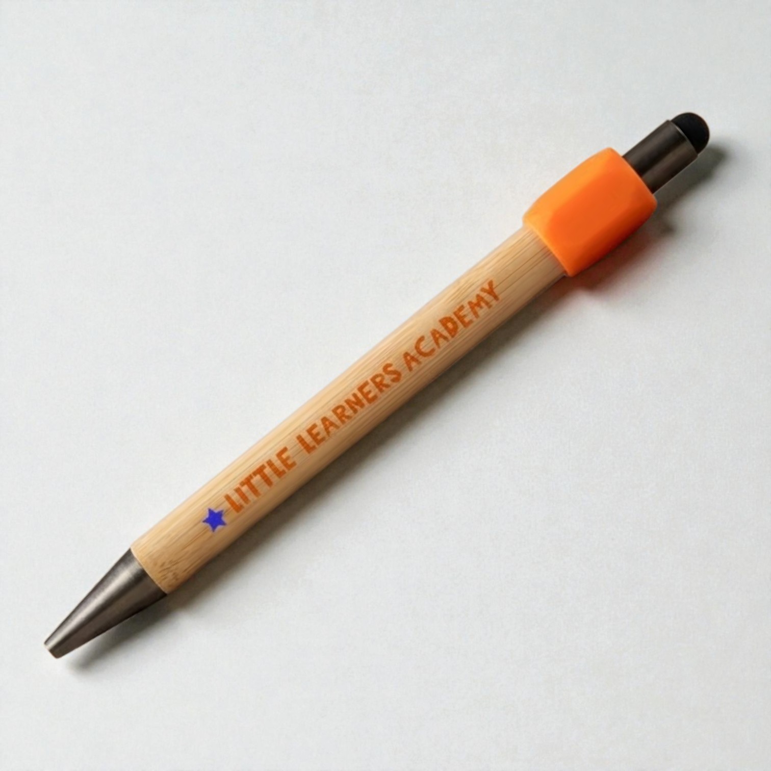 A pen with LITTLE LEARNERS ACADEMY printed on it, an orange grip, and priced under $5.
