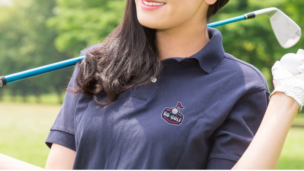 Woman in a navy corporate golf shirt holding a club, smiling—perfect for repeated wear outdoors.