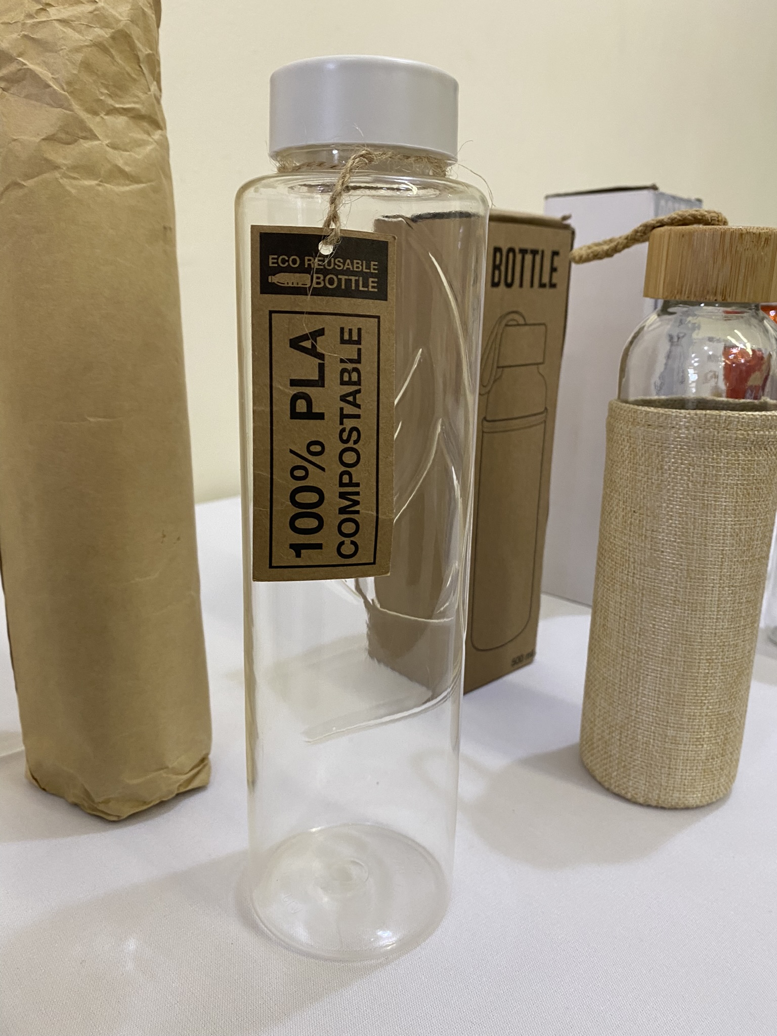 Clear bottle with a white cap, best size bottles tag reads 100% PLA Compostable on white surface.