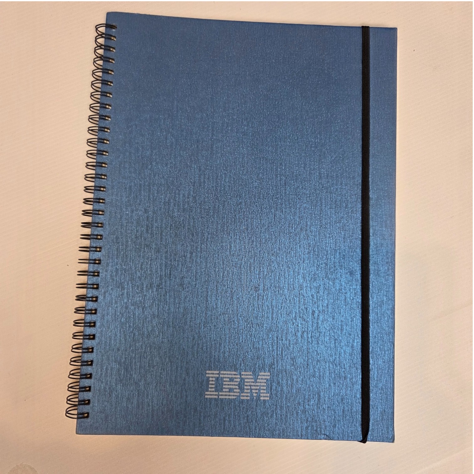 Blue spiral IBM notebook with an elastic band, showcasing IBM's quality products.