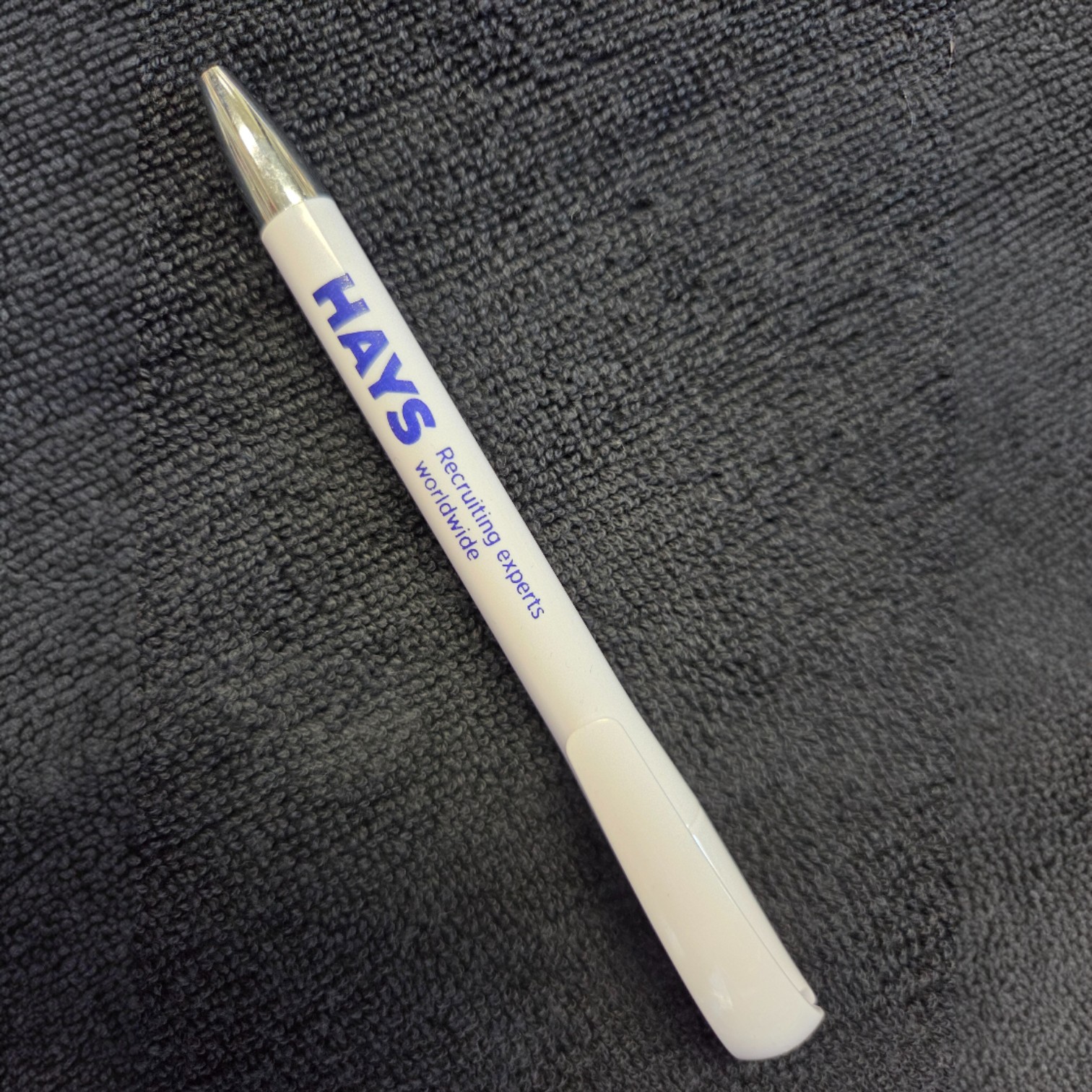 White HAYS pen with blue text on a dark textured surface, showcasing quality products.