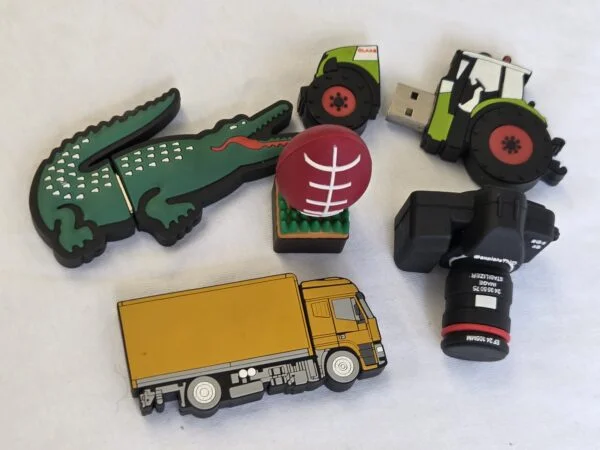 Four novelty Twist USB Drives: a crocodile, a tractor, a rugby ball, and a yellow truck.