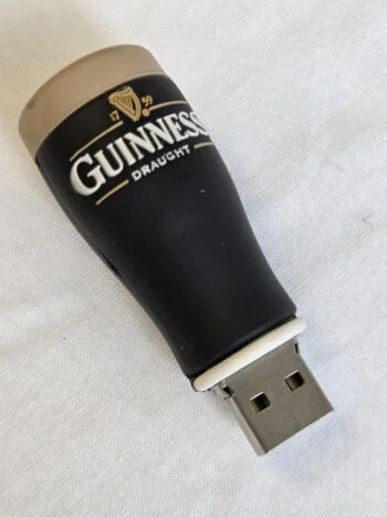 A Twist USB Drive shaped like a pint of Guinness beer on a white surface.