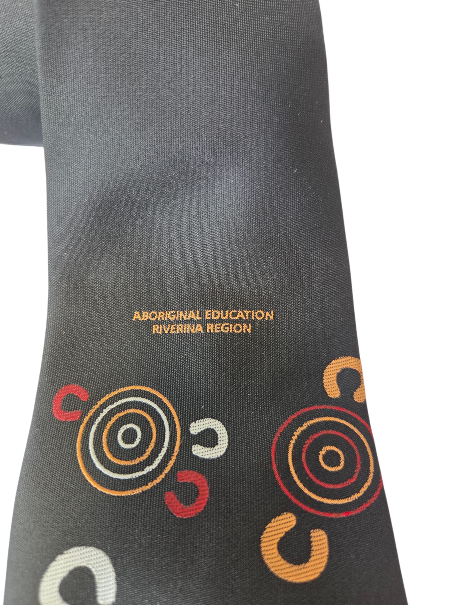 Black fabric with spiral and arc patterns, featuring Aboriginal Education Riverina Region text.