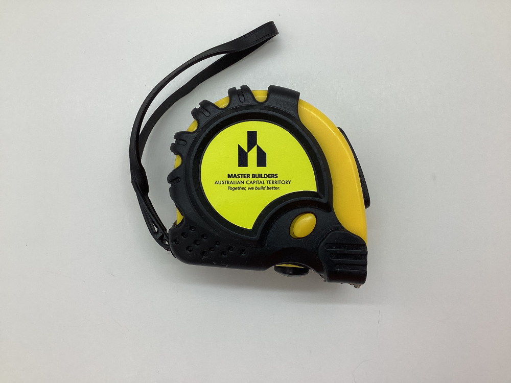 Yellow and black tape measure with Master Builders ACT logo on a white background.