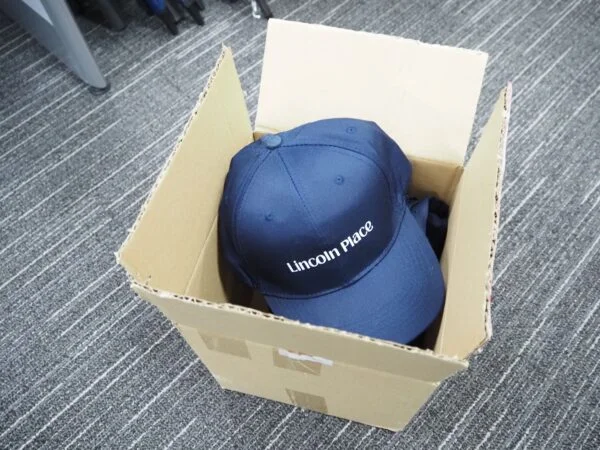 Navy blue Lincoln Place cap in box—avoid production delays by placing bulk orders early.