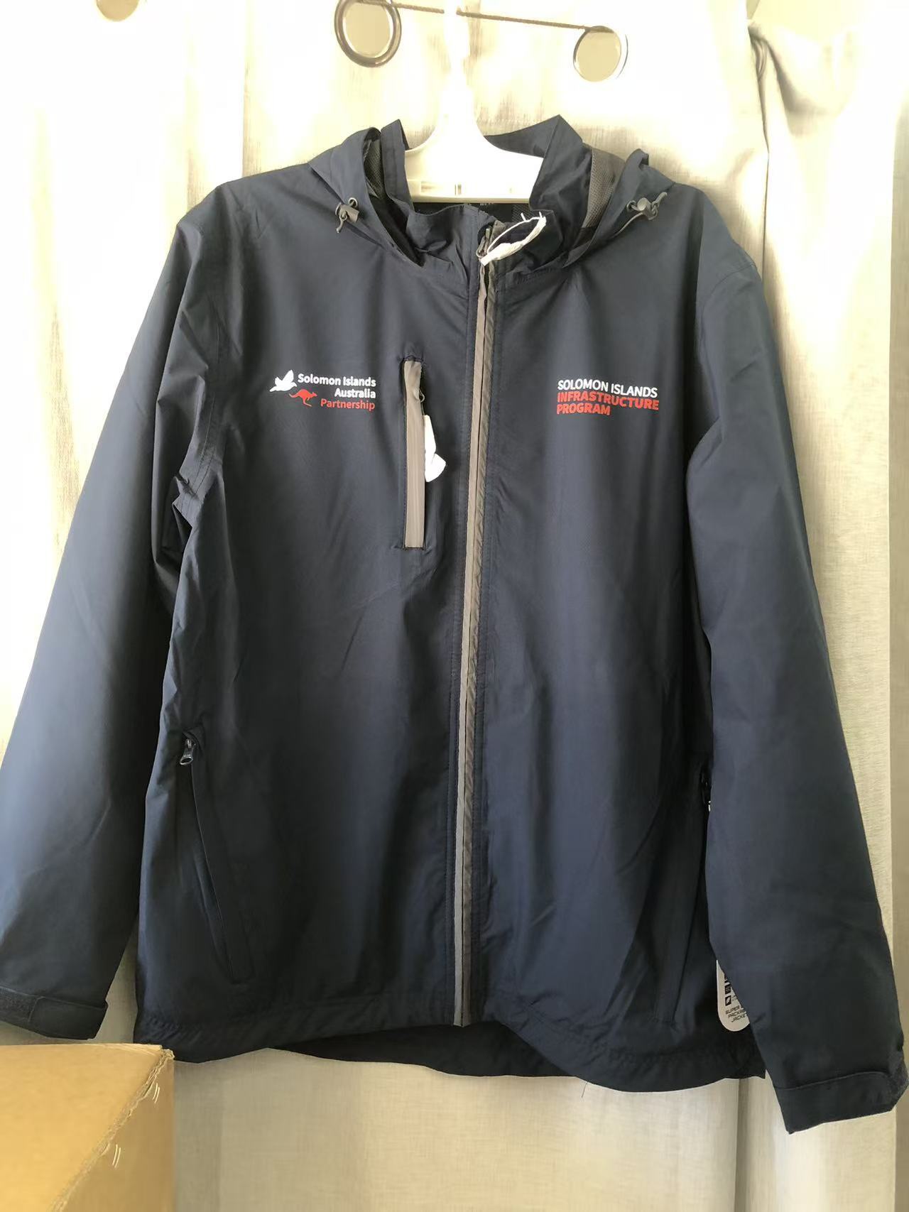 Navy blue Solomon Islands Red Cross jacket, SIIP-branded, hanging against a light curtain.