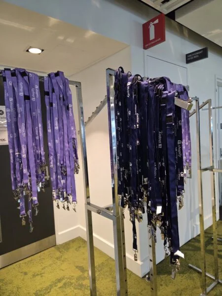 Two racks display conference merchandise quantities: one full of lanyards, one nearly empty.