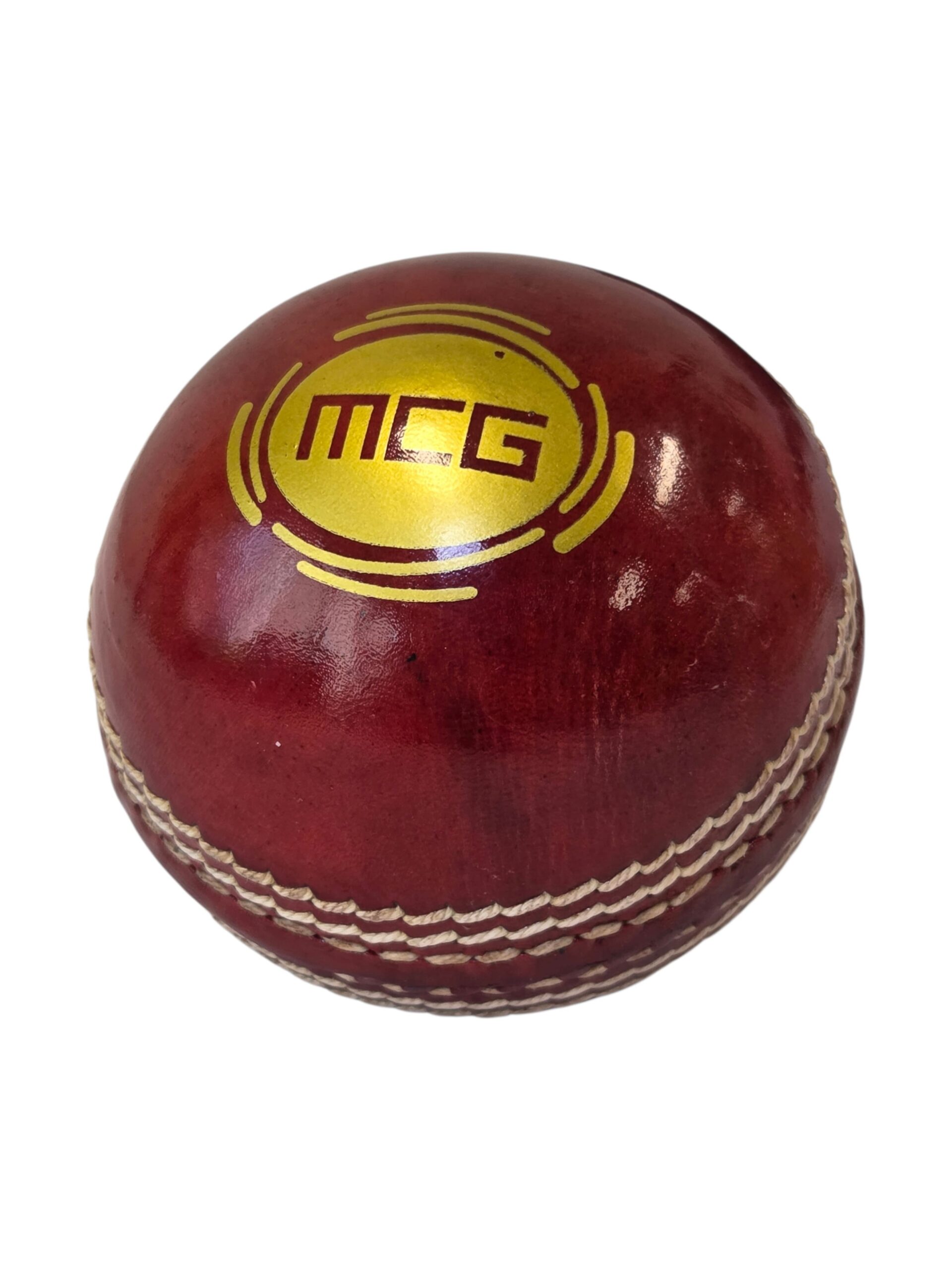 Red cricket ball with Melbourne Cricket Organisation logo and white stitching on white background.